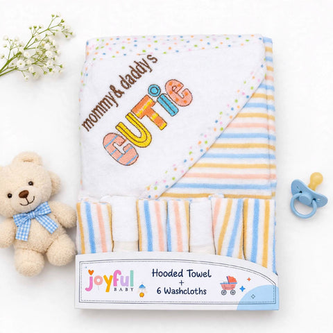 A folded baby hooded towel set with six washcloths, featuring pastel striped patterns and embroidered text reading 'mommy & daddy's CUTIE' on a white hood. The set is displayed on a white background with a small teddy bear, baby flowers, and a pacifier as