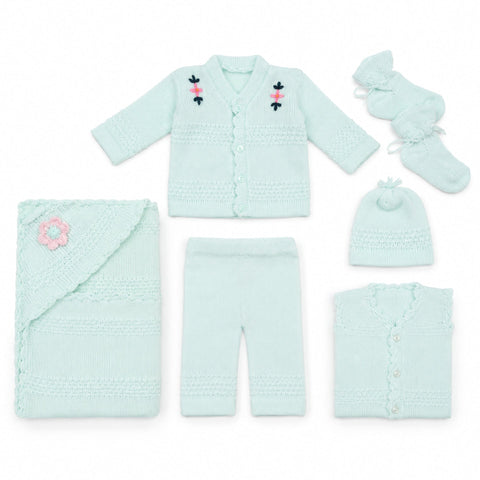A light mint green knit baby clothing set laid out on a white background, including a cardigan with embroidered floral details, pants, a folded blanket with a pink flower accent, a folded button-front top, a beanie, and booties.