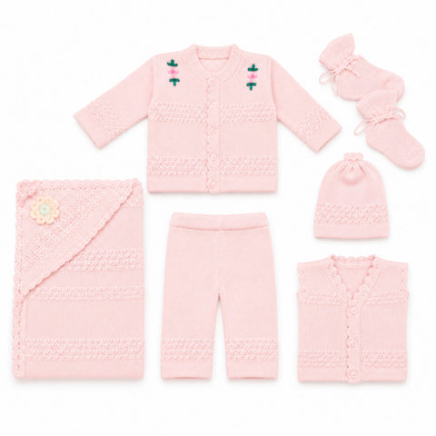 A coordinated baby knit clothing set laid out on a white background, including a long-sleeve cardigan, pants, a hat, a sleeveless vest, a swaddle wrap, and booties. The set is light pink with textured knit patterns and small embroidered floral details on 
