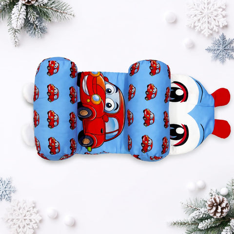 A plush baby sleeping bag or pillow cover featuring a light blue background with a repeating pattern of red cartoon cars and a large red-and-white character face peeking out on one end, styled on a white background with holiday decorations.