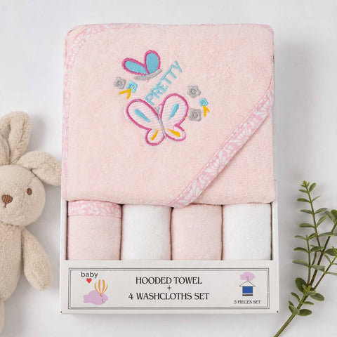 A boxed baby towel set on a white background, featuring a folded pink hooded towel with embroidered butterfly and 'PRETTY' design, plus four rolled washcloths underneath in matching pale pink and white. A plush bunny is partially visible on the left and a