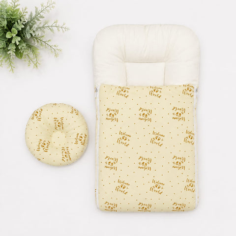 A baby footmuff in pale yellow with a repeating brown 'Welcome to the World' script and dot pattern, shown with a matching round cushion on a white background.