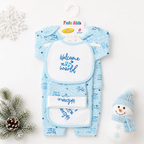 A twin baby onesie and bib set in light blue with a snowflake pattern, displayed on a white background with holiday props including a snowman decoration, pine branch, and snowflake ornament. The packaging card at the top reads 'Twin Kids'.