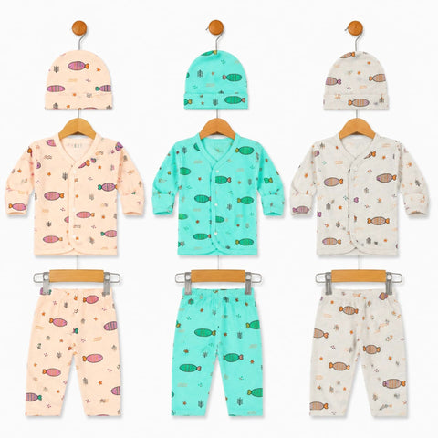 Three baby clothing sets displayed on wooden hangers against a white background, each set including a hat and matching pants. The left set is light peach with pink fish prints, the center set is mint green with green fish prints, and the right set is crea