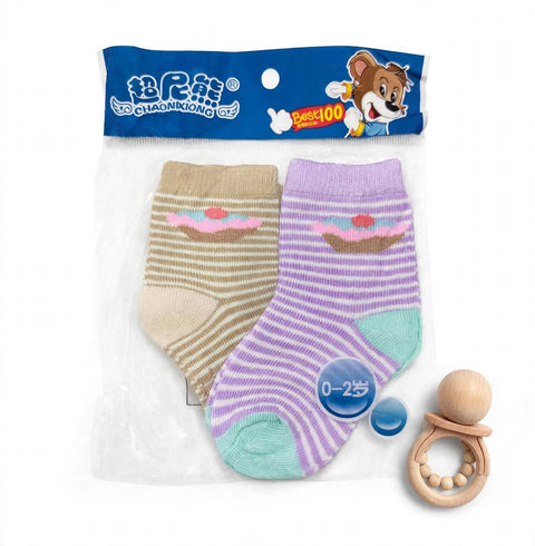 A pair of baby socks in a clear plastic package with a blue header card. One sock is beige and white striped with a pink cupcake print, and the other is purple and white striped with a pink cupcake print and mint green toe.