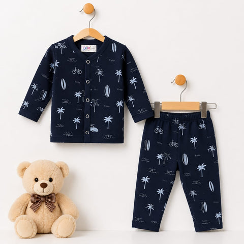 A two-piece baby clothing set consisting of a long-sleeve button-front cardigan and matching pants, both in navy blue with a white palm tree, bicycle, and surfboard print. The set is displayed on wooden hangers against a white wall, with a plush teddy bea