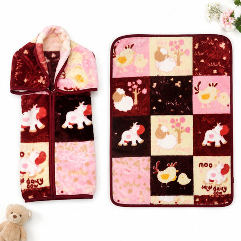 A plush fleece blanket with a patchwork design featuring cartoon animals and trees in pink, burgundy, and cream, shown both flat and folded with a zipper pocket on the front. A small teddy bear is at the bottom left, and flowers are at the top right, on a
