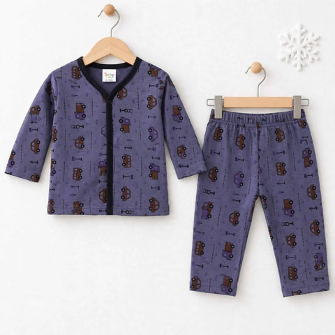 A two-piece children's pajama set hanging on wooden hangers against a white wall. The set includes a long-sleeve top and matching pants in a dusty purple fabric with an all-over print of brown and purple toy cars and small icons, finished with a black col