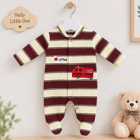 A baby footed sleeper with horizontal burgundy and cream stripes, featuring a red fire truck graphic and 'LITTLE' text on the chest, hanging on a white hanger against a light wall with a teddy bear and decorative cloud sign nearby.
