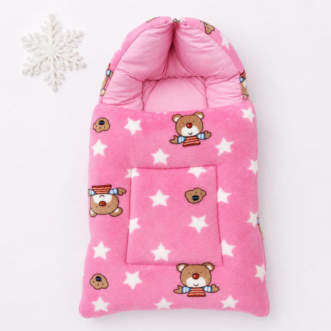 Pink fleece baby sleeping bag with a teddy bear and white star pattern, featuring a front pocket and hooded design, shown on a white background with a decorative snowflake.