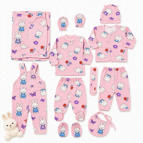 A coordinated baby clothing set laid out on a white background, including a pink long-sleeve top, matching pants, cardigan, hat, bib, booties, mittens, and overalls, all printed with white rabbits, purple butterflies, and small red/orange flower motifs. A