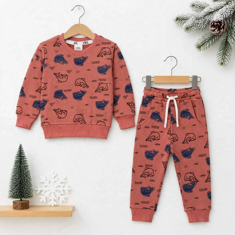 A children's two-piece clothing set featuring a long-sleeve sweatshirt and matching jogger pants in a dusty rose color with a navy blue seal pattern, displayed on wooden hangers against a white background with holiday decorations.