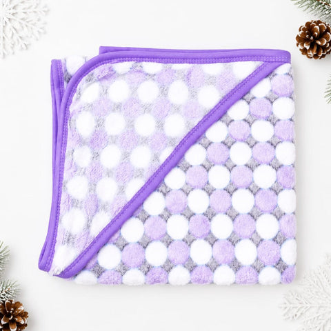 A folded plush blanket with a purple and white polka dot pattern and solid purple trim, displayed on a white background with decorative pinecones and snowflakes.