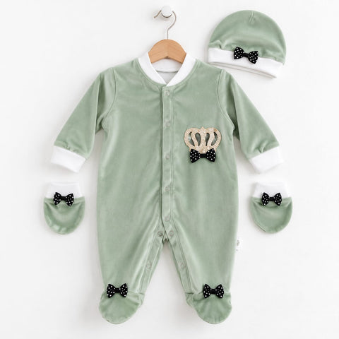 A baby footed sleeper set in sage green velvet, featuring a crown and bow applique on the chest, matching booties, a bonnet, and a hanger, displayed on a clean white background.