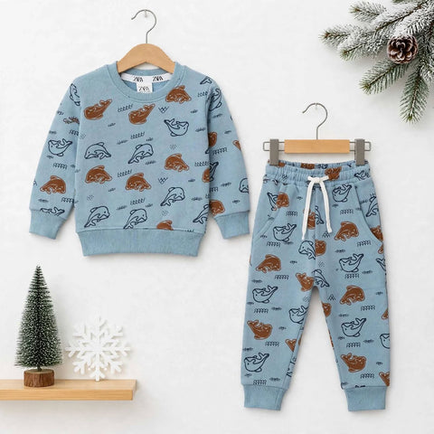 A children's two-piece pajama set hanging on wooden hangers against a light wall. The set includes a light blue long-sleeve sweatshirt and matching jogger pants, both printed with a pattern of brown and black polar bears.