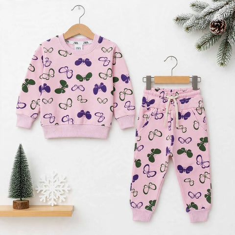 A children's two-piece lounge set consisting of a pink sweatshirt and matching jogger pants, both decorated with a purple and green butterfly pattern. The sweatshirt is shown on a wooden hanger on the left, and the pants on a metal hanger on the right, se