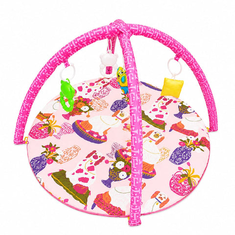 A baby activity gym with a pink frame and a round play mat featuring a colorful fashion-themed print, complete with hanging toys.