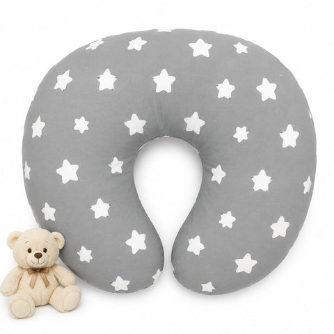 A U-shaped baby nursing pillow in gray with a white star pattern, shown on a white background next to a small beige teddy bear.