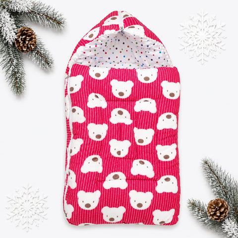 A pink striped hooded baby blanket or swaddle with a white teddy bear face pattern, shown flat on a white background with decorative pine branches, pinecones, and white snowflake cutouts.